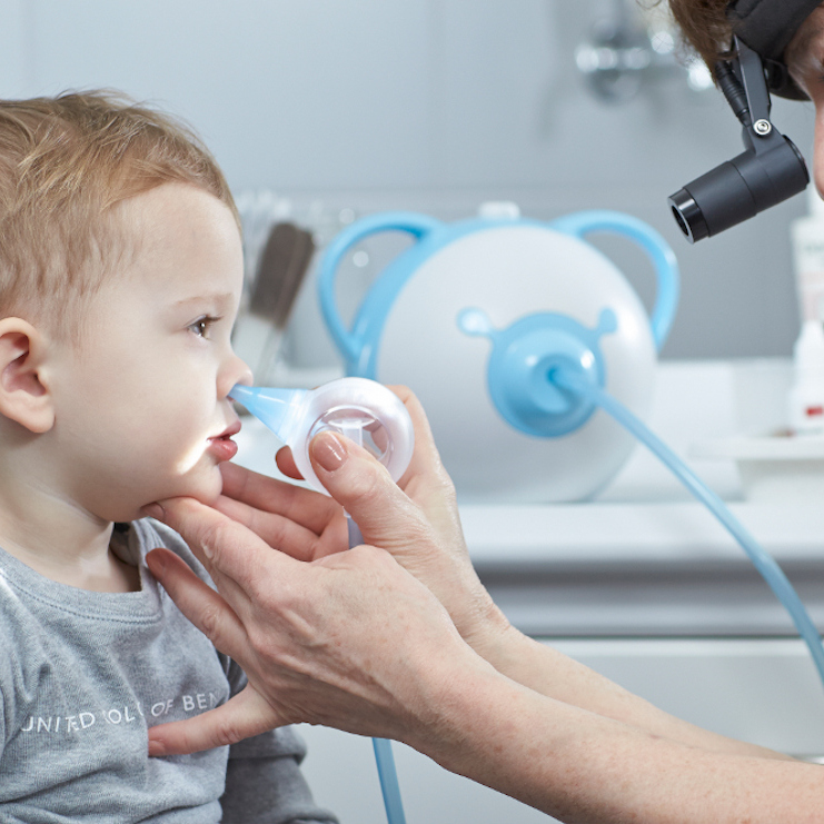 An ENT specialist cleaning a little boy's nose with the help of a Nosiboo Pro electric nasal aspirator.